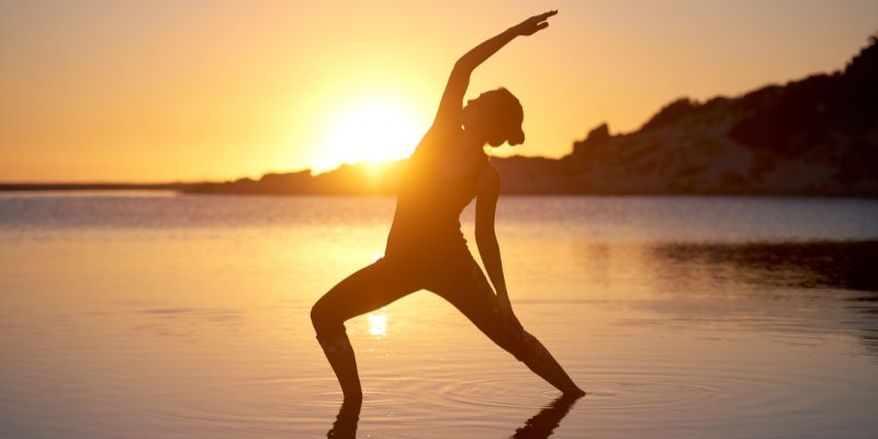 Woman doing yoga at sunset