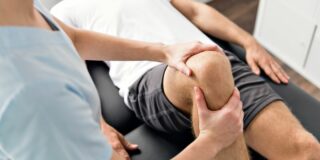 Physiotherapist manipulating knee of patient