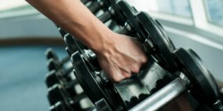 Close up shot of person picking up dumbbells